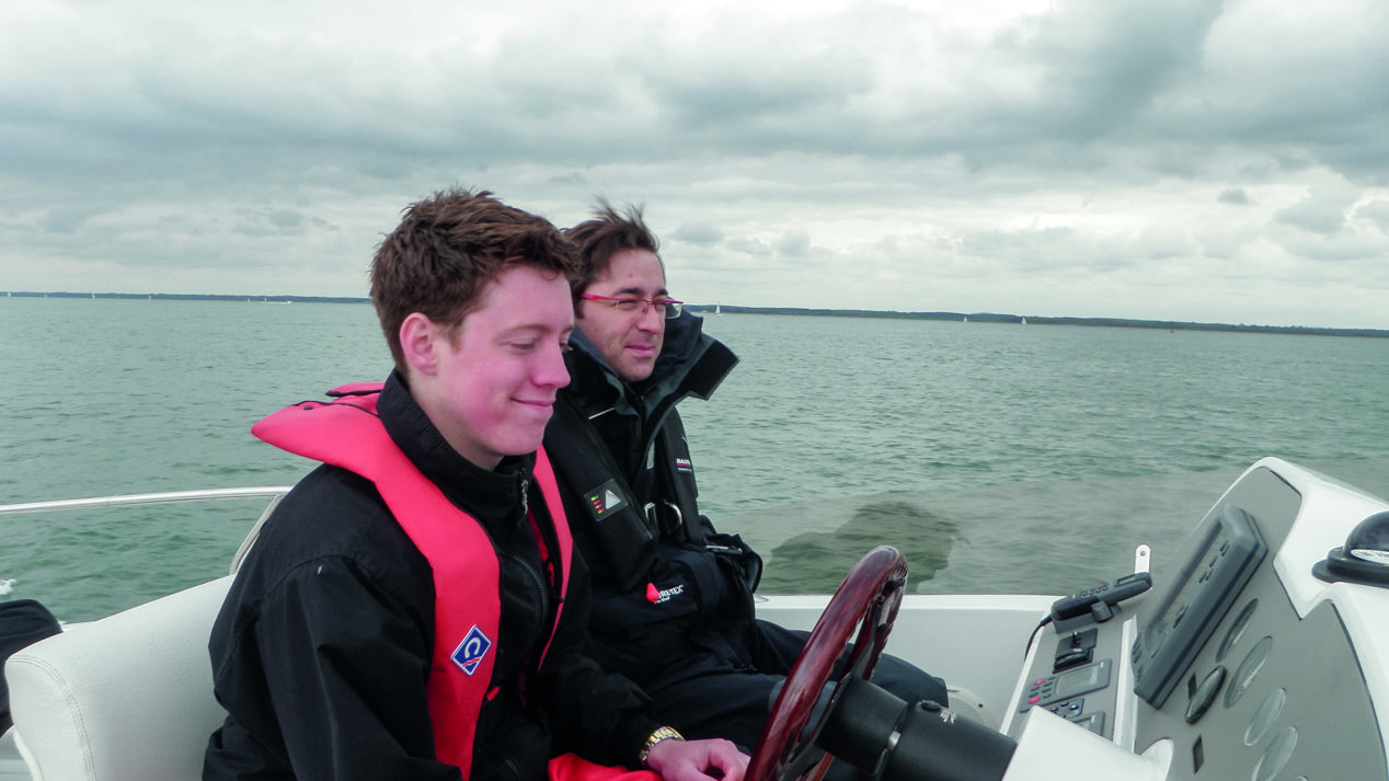 Two sailors sat at the helm of powerboat 