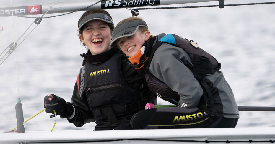 	An image of two young girls laughing while sailing the boat