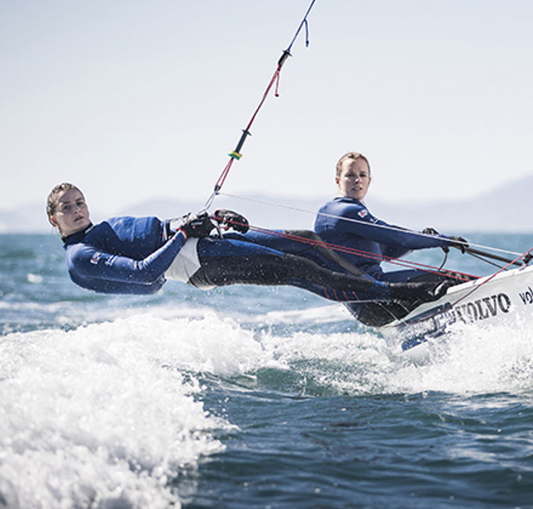 Two watersports enthusiasts hanging from their boat