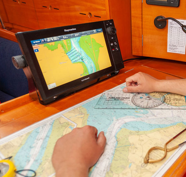 man looking at map laid out in front of him, along with electronic navigation device