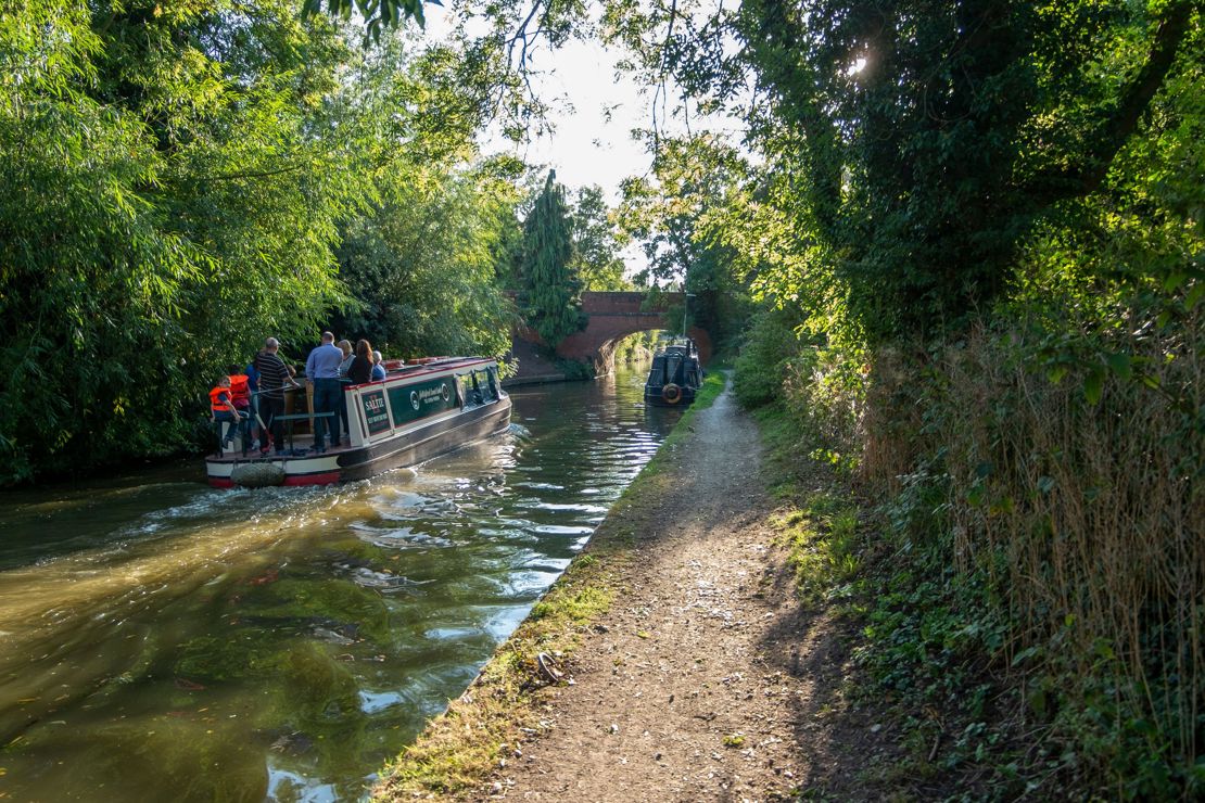 Canal boat on inland waterways sailing towards bridge