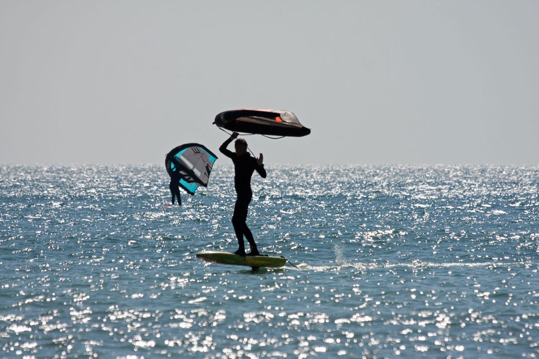 a silhouette of two wing surfers travelling through sparkling water