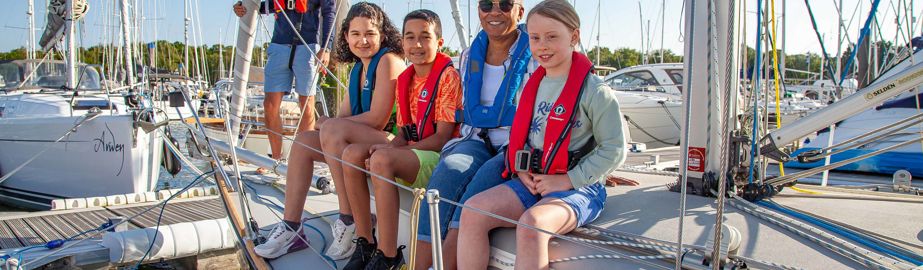 Smiling family sat on the edge of their boat 