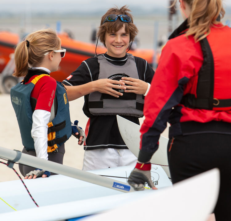 Children smiling on the beach with their instructor
