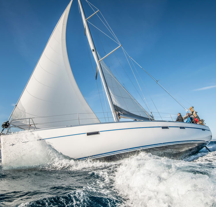 One white sailing yacht floats on the sea with waves and spray. The view from the side