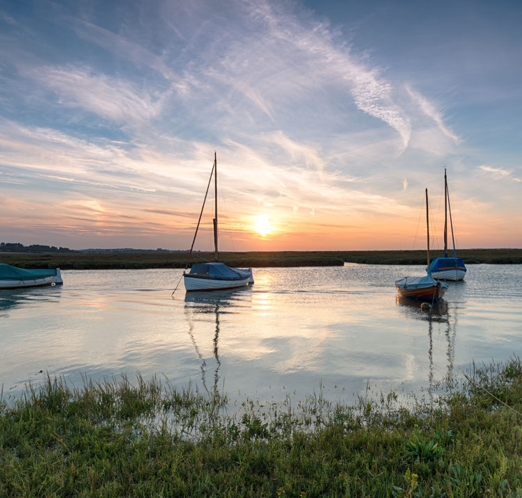 Sail boats anchored in lake at sunset