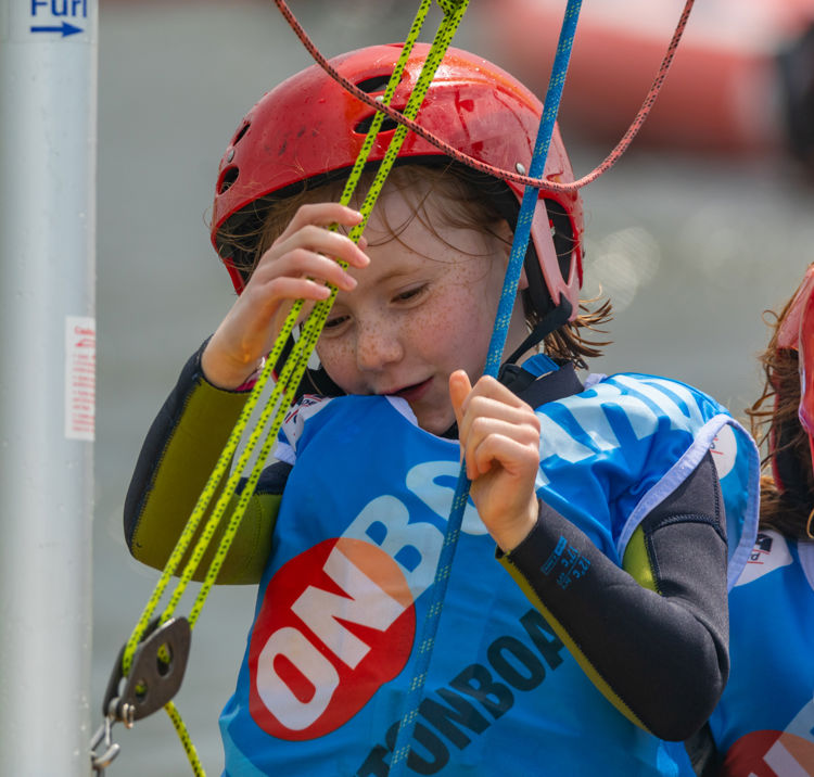 young child holding on to ropes wearing an onboard lifejacket