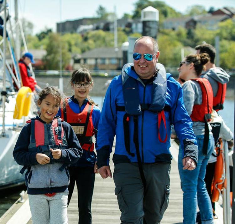 man and two young girls walking along the dock