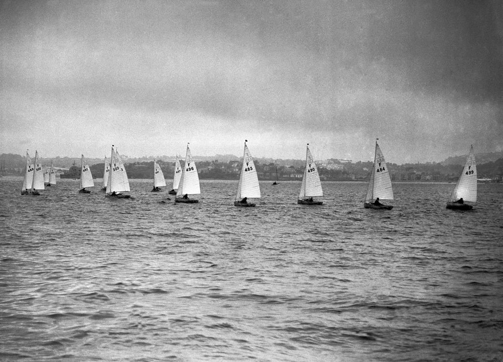 Black and white photo of wooden dinghies preparing for a race