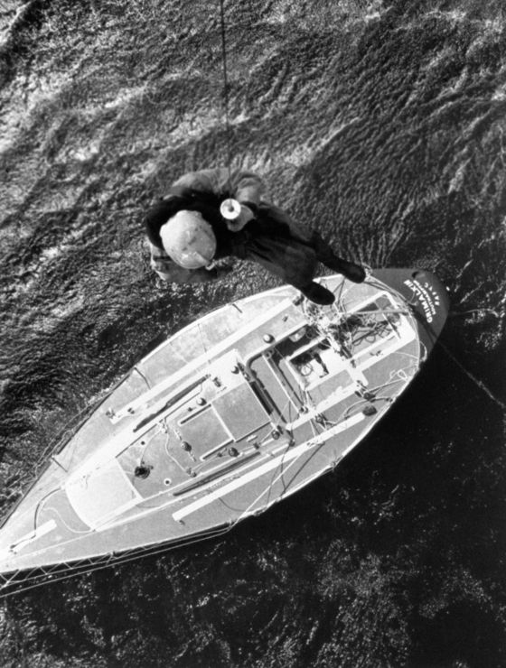 Black and white image of man being lowered onto boat