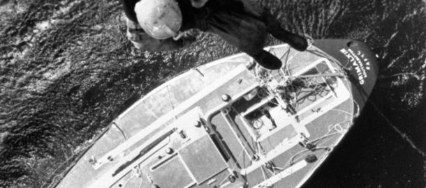 Black and white image of man being lowered onto boat