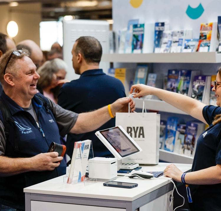 Mid shot of customers purchasing a book at RYA stand
