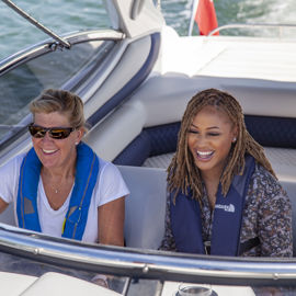 A close up of two smiling women in a motorboat