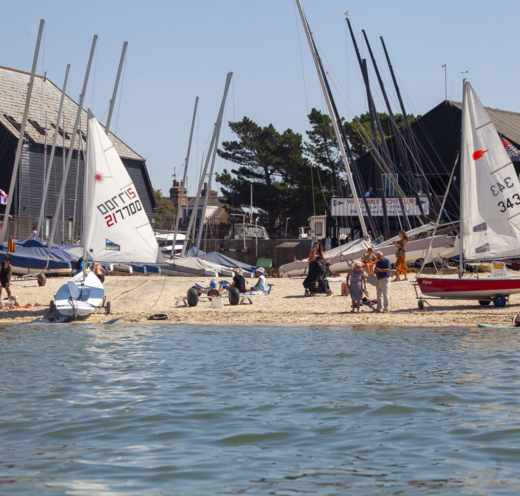 	a wide angle shot of a sailing club preparing sailing boats on a sunny day to go sailing.