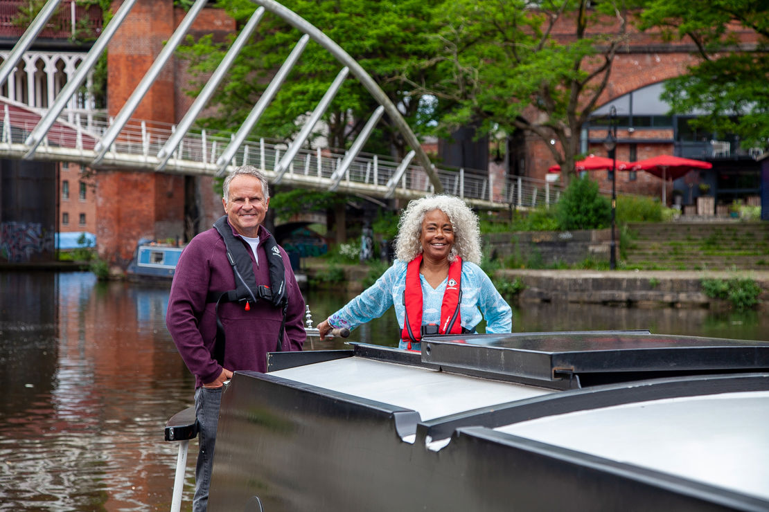 Long shot of two sailors on canal boat smiling