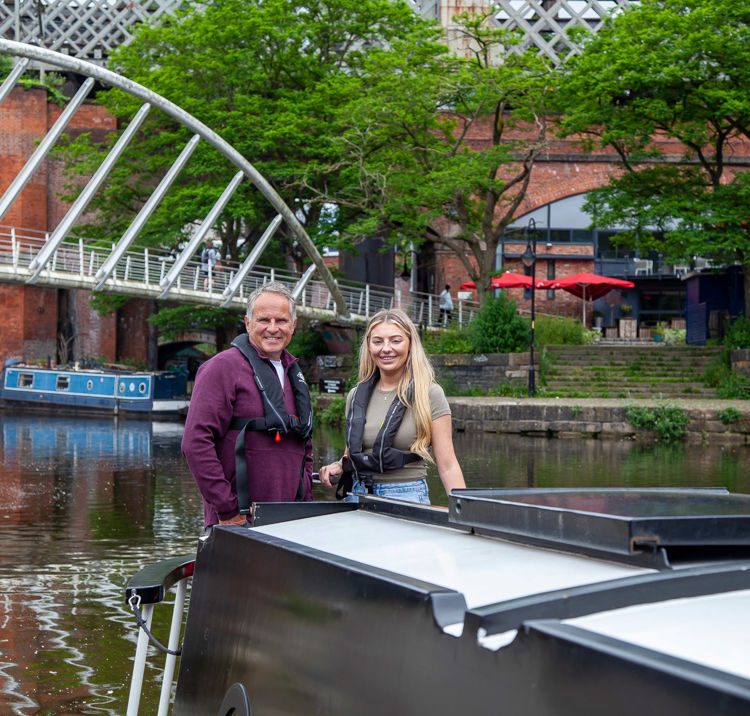 Long shot of two sailors on canal boat smiling