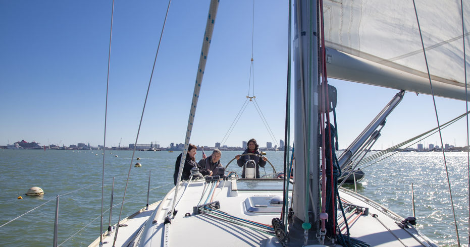 3 people sailing a boat on the open water