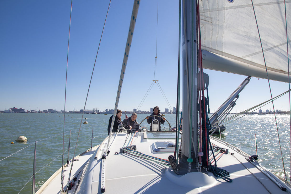 3 people sailing a boat on the open water