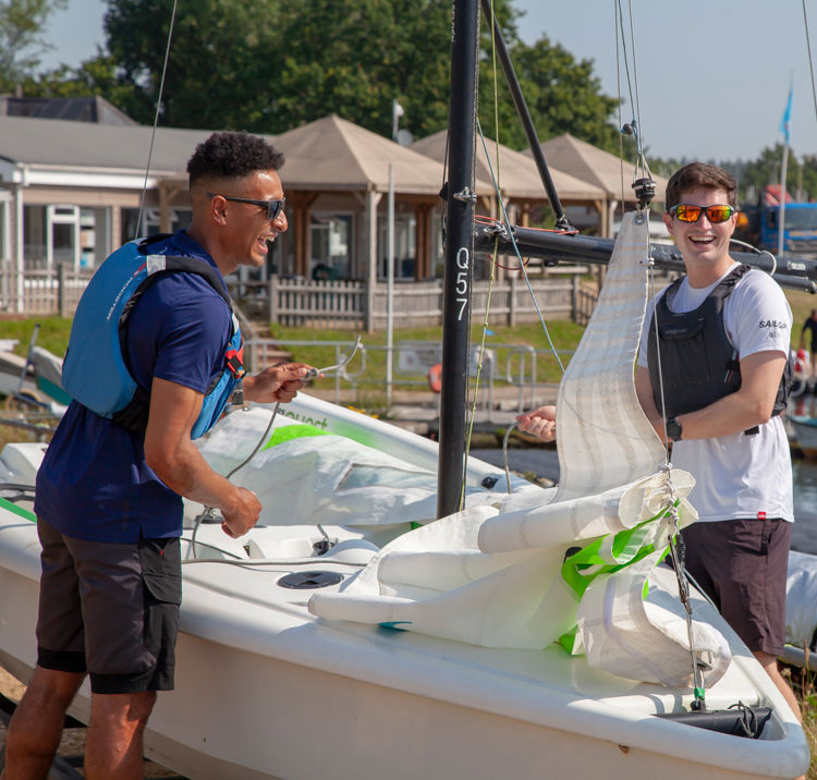 Long shot of four sailors laughing and preparing a sailboat
