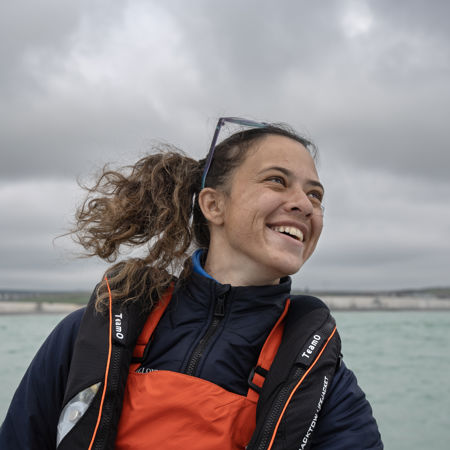 Mid shot of female sailor smiling with the sea behind her