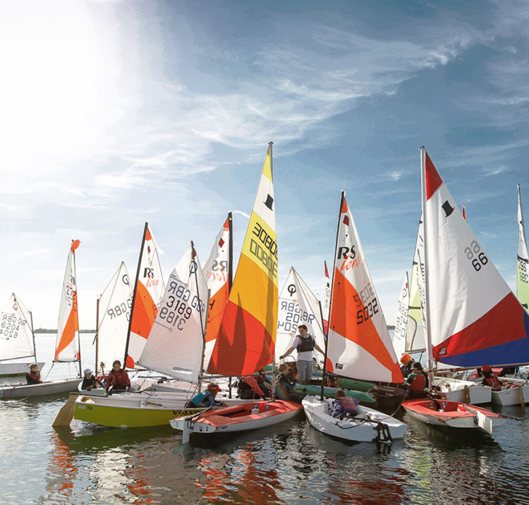 Wide shot of a junior dinghy racing fleet in the sunshine