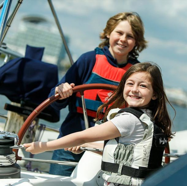 young girl and boy on sailing yacht, the boy is steering and the girl is puling the rope