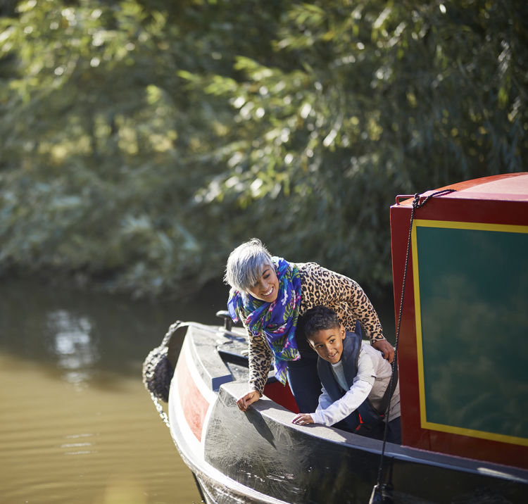 mother and son leaning over the side of a canal boat looking happy