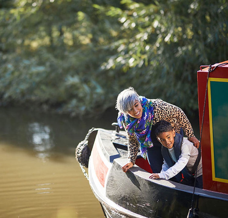 Mother and son leaning over the side of a narrowboat.