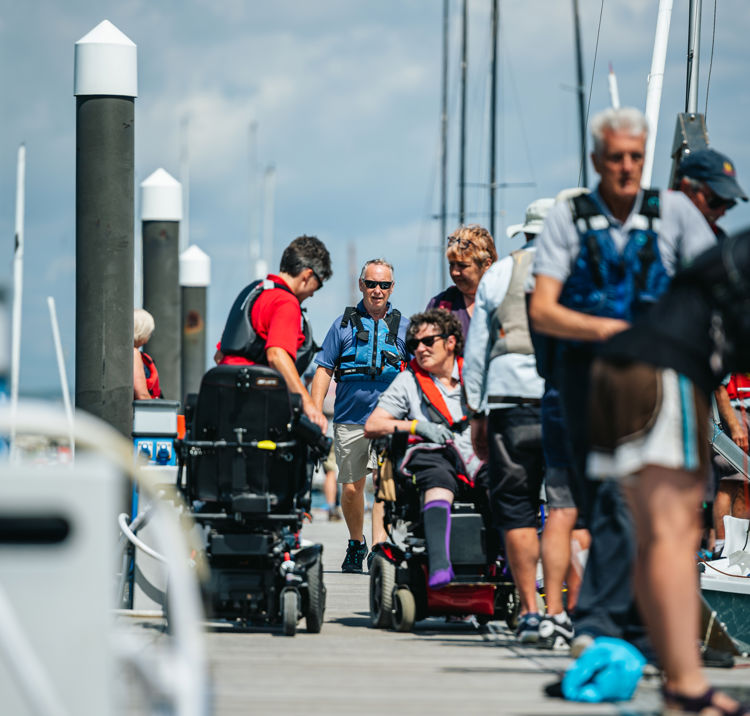 wheelchair using sailors on deck walking towards boats