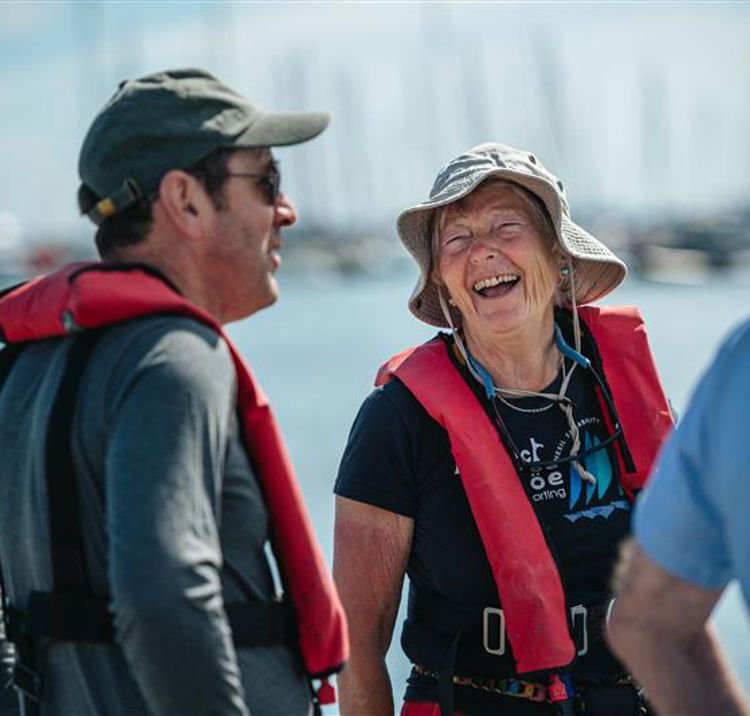 Mid shot of two volunteers laughing and smiling near the water