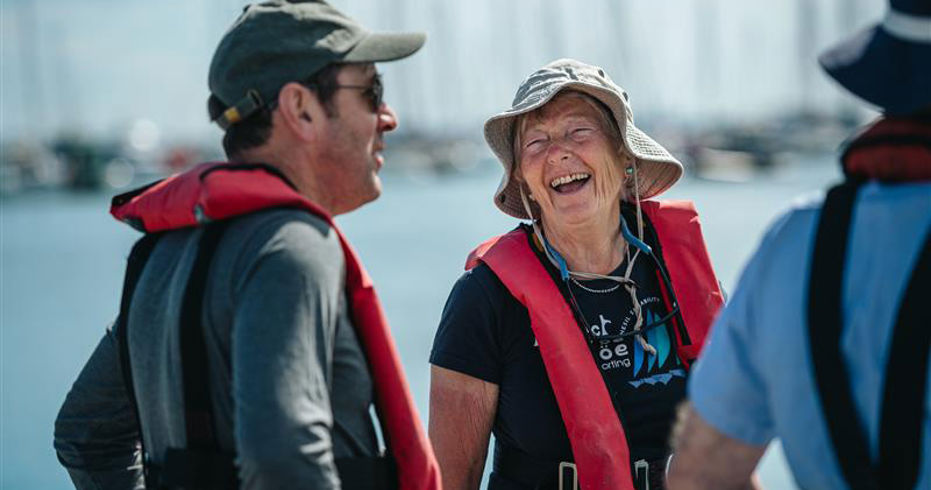 Mid shot of two volunteers laughing and smiling near the water