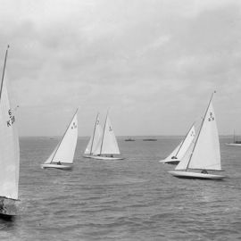 Black and white image of traditional wooden sailing boats travelling across the water