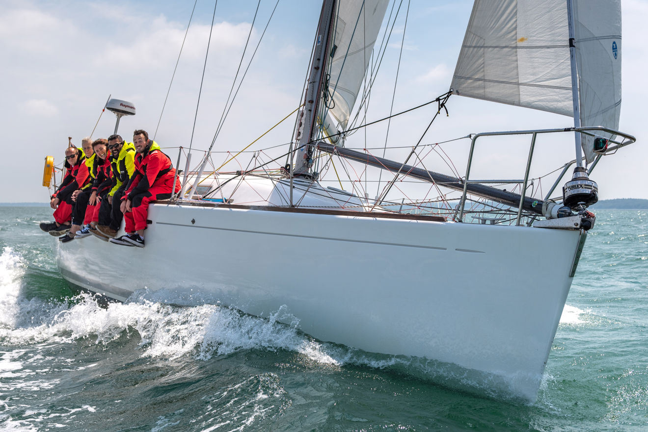 sail cruising course mates sitting on the edge of their boat