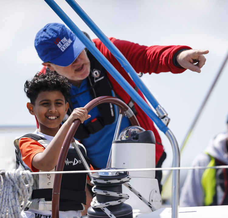 young boy steering boat with help from instructor