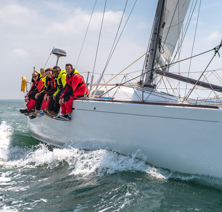 Sail cruising crew hanging off the side of their boat