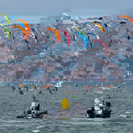 Kite surfers racing with a support rib