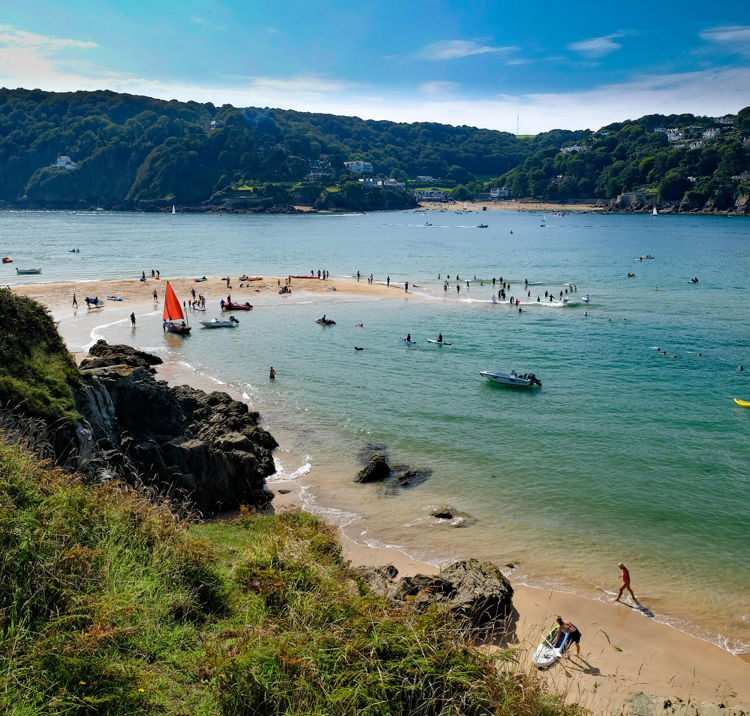 Boats and people on the sand bar at the entrance to Salcombe Estuary, Devon, UK