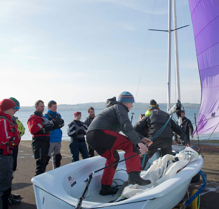 A volunteer on a dinghy showing a group how to use it