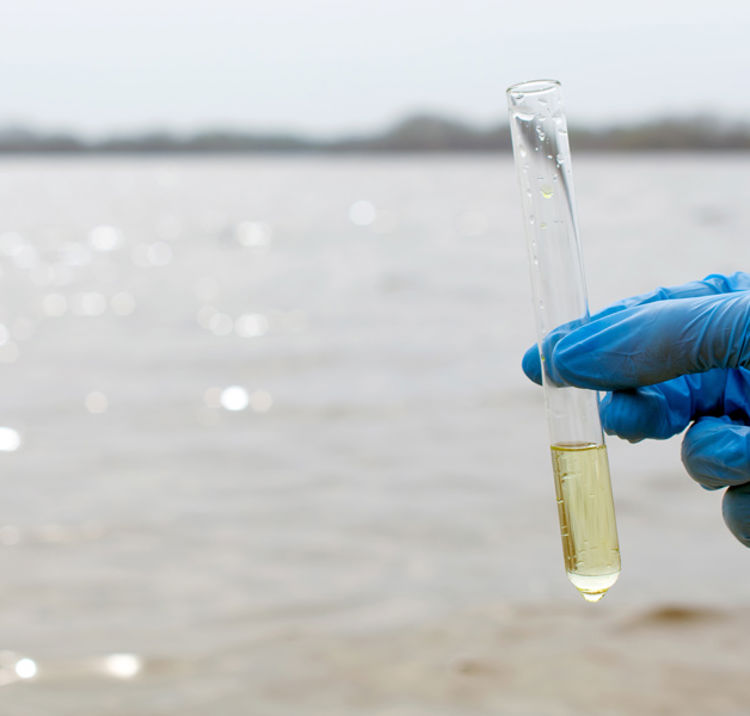 Picture of a gloved hand holding a sample of river water